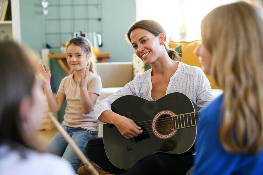 Group of homeschooling children with teacher having music lesson indoors, coronavirus concept.