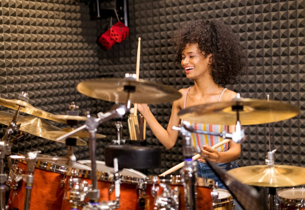 Laughing vivacious young woman playing drums