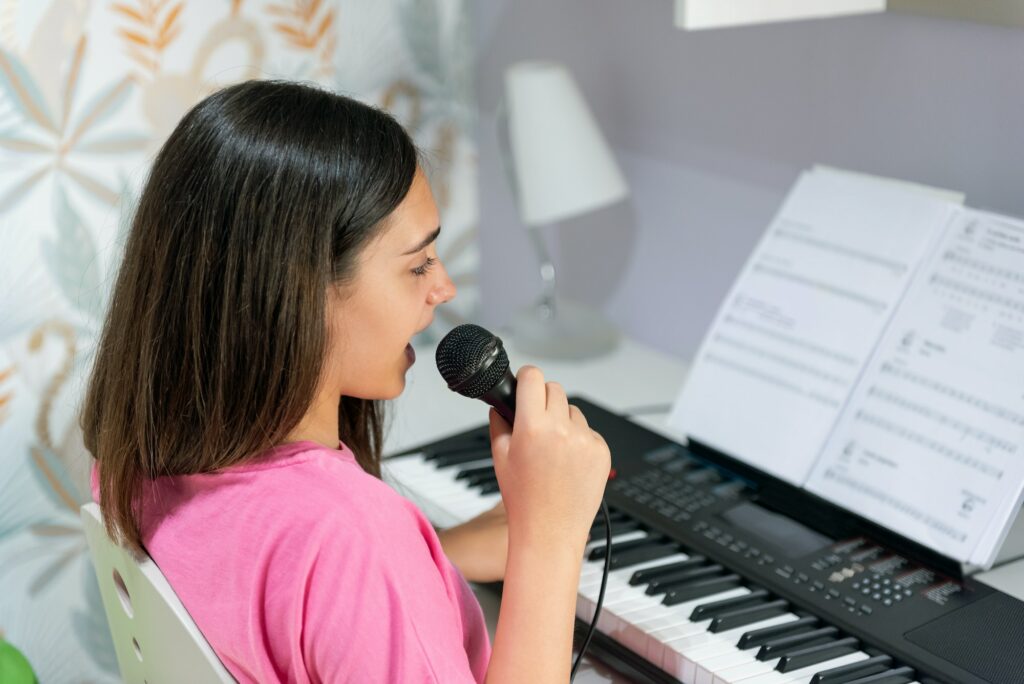 Young girl playing piano and singing at home