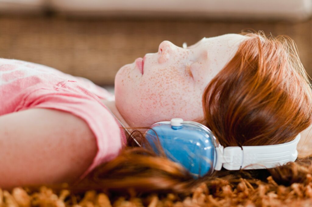 Girl listening to headphones on carpet